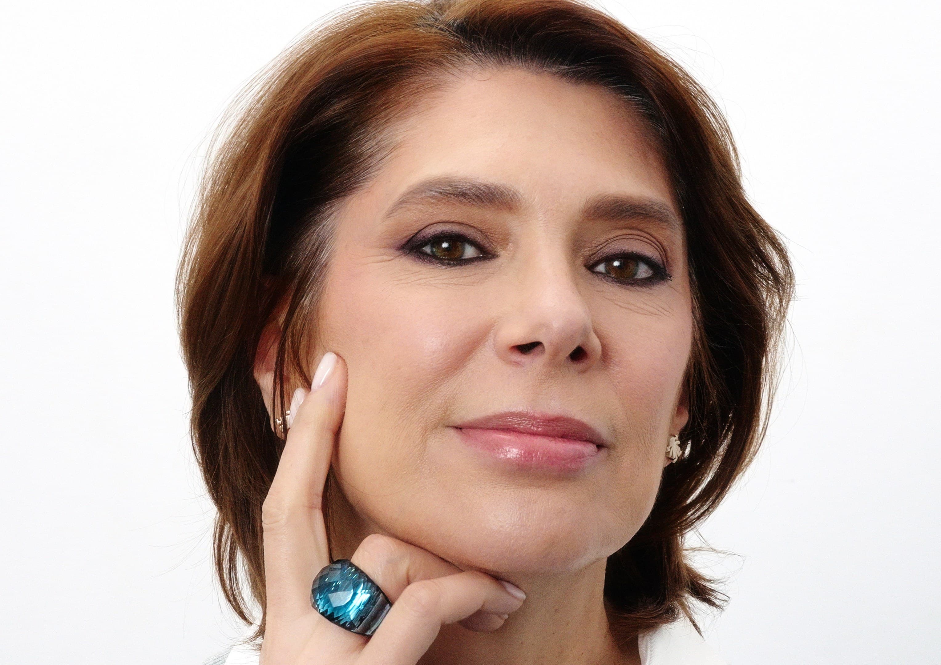 Aura, cu machiajul de seară Your Smokey Signature: ochi fumurii și buze nude, cu bărbia sprijinită în palmă.