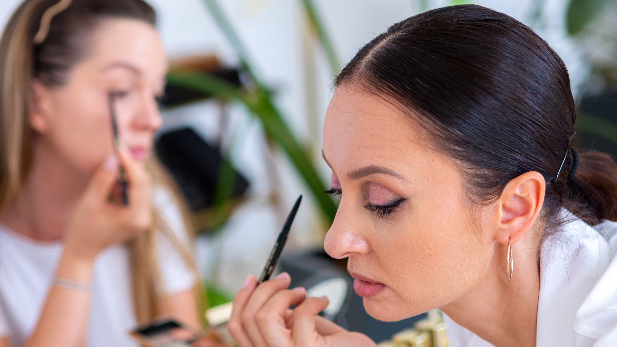 Tania Cozma demonstrating eyeliner at the workshop while a participant follows along in the background.