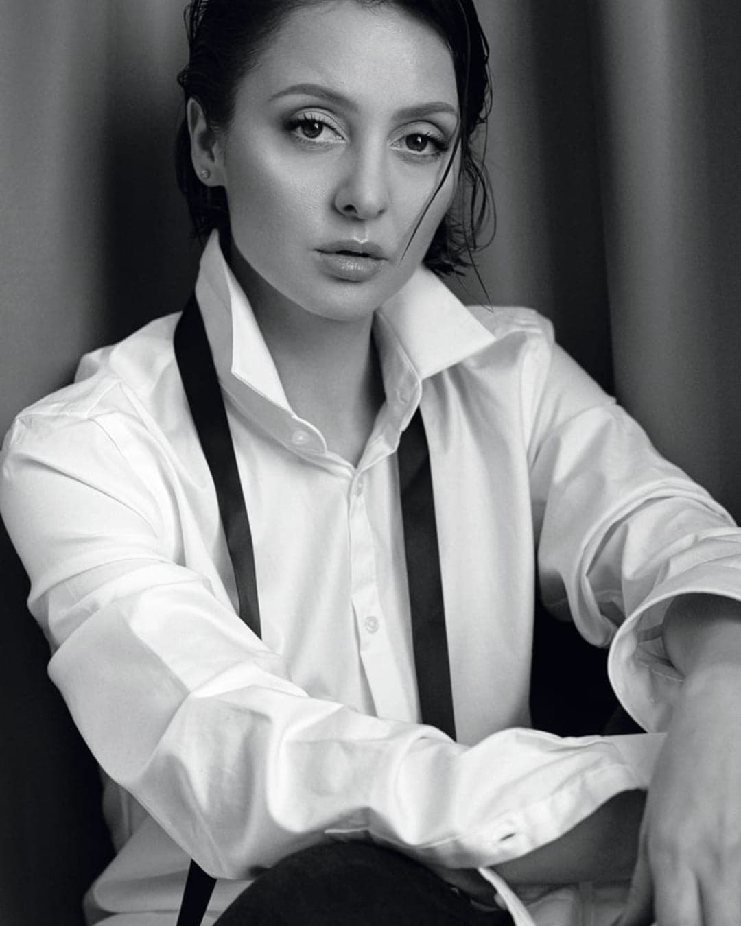 Portret alb-negru al Taniei Cozma, cu părul dat pe spate, în cămașă albă și cravată lăsată liberă.